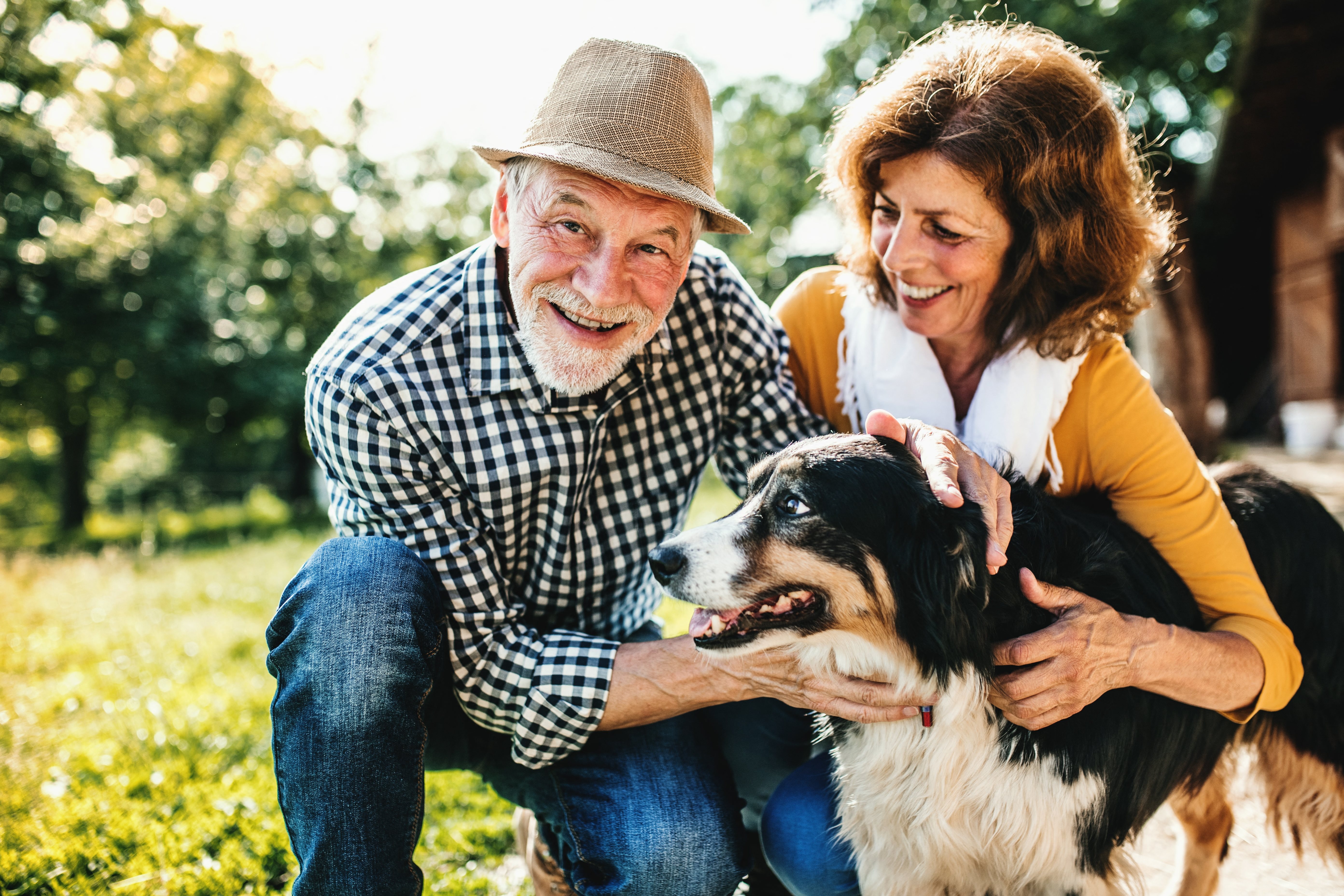 a man and woman petting a dog outdoors at a senior apartment community