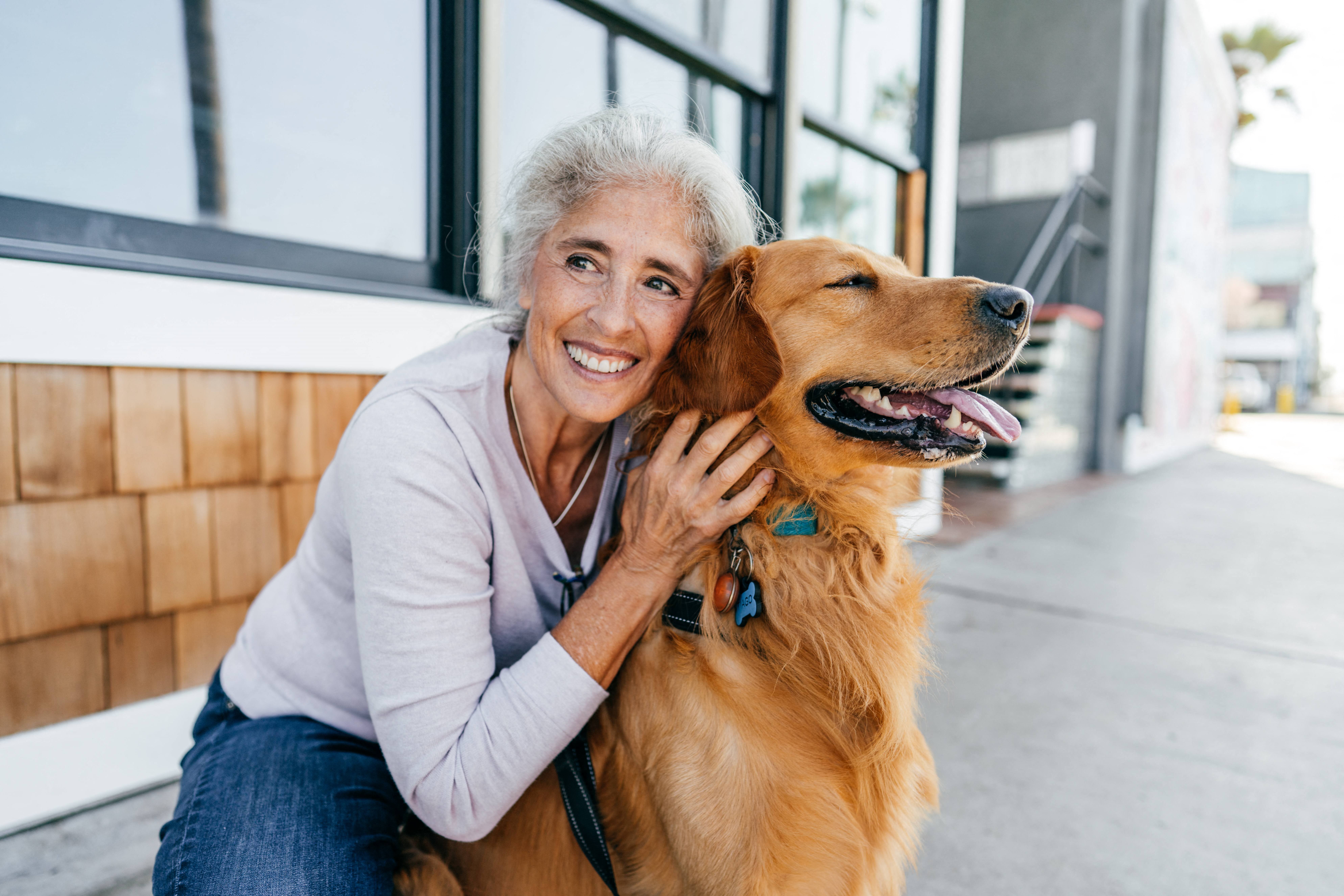 an older woman sitting with her dog outside at a senior apartment community