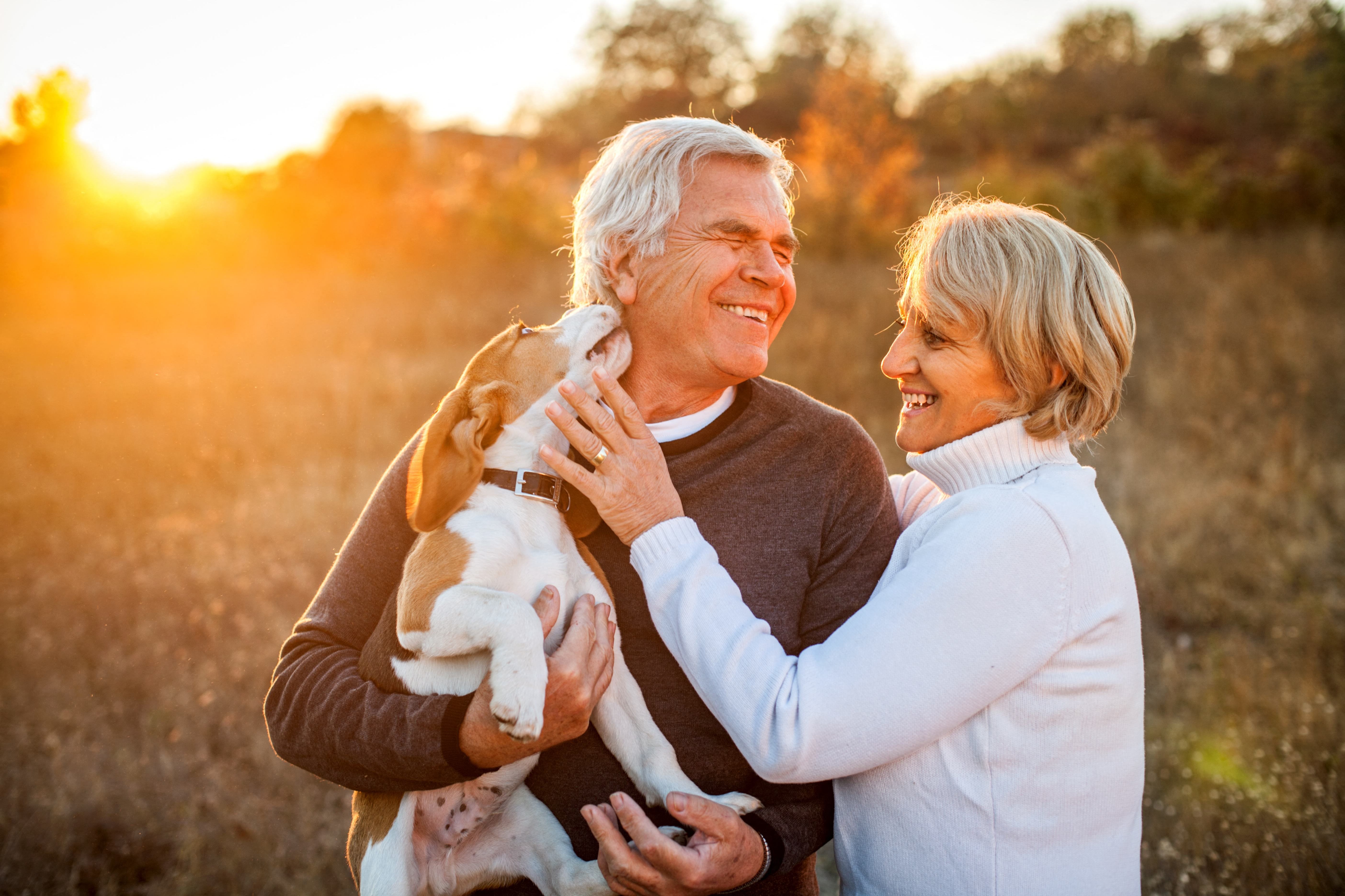 an older couple playing with their dog outside at a senior apartemnt community