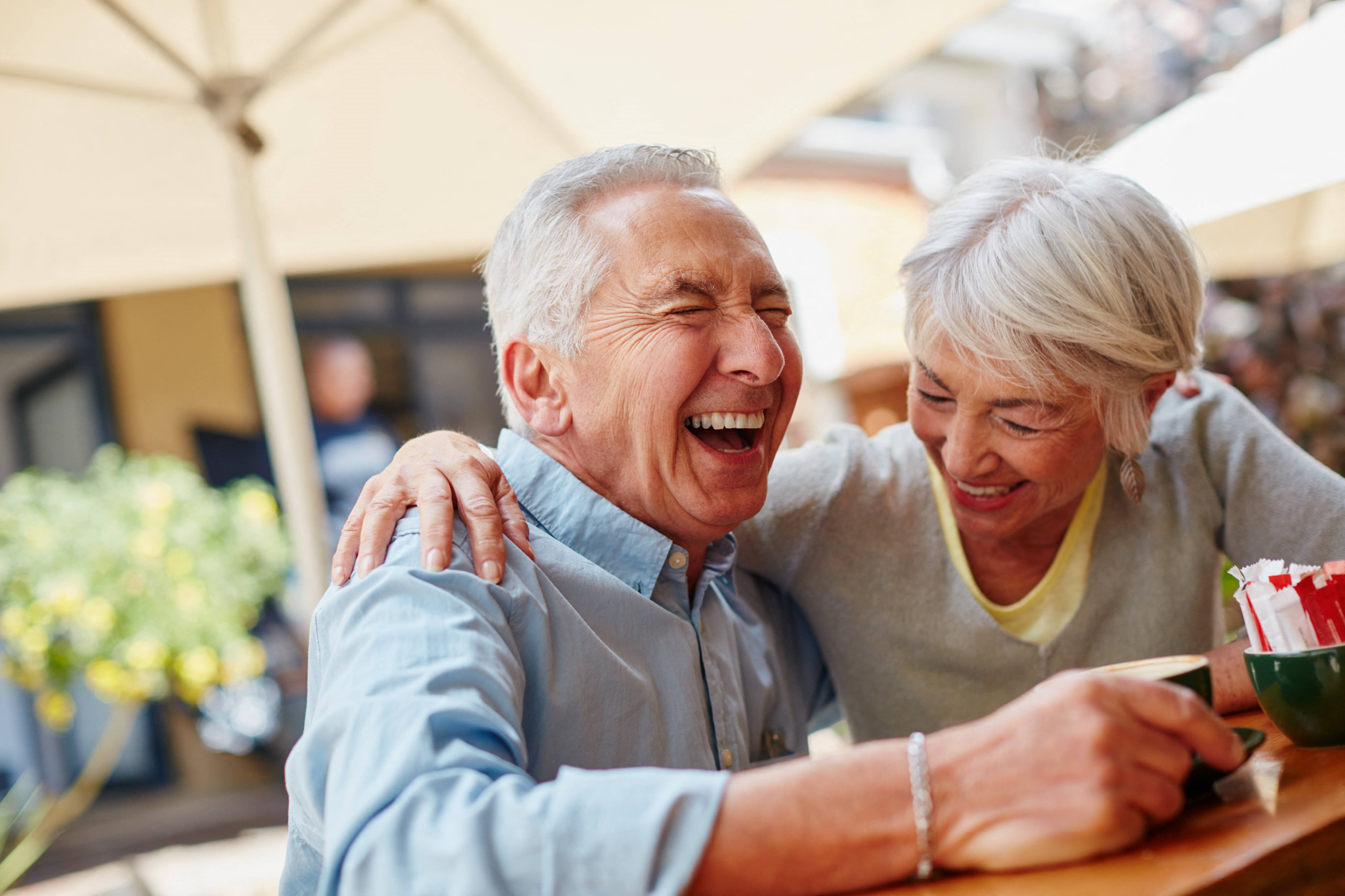 an older couple laughing together outside at a senior apartment community