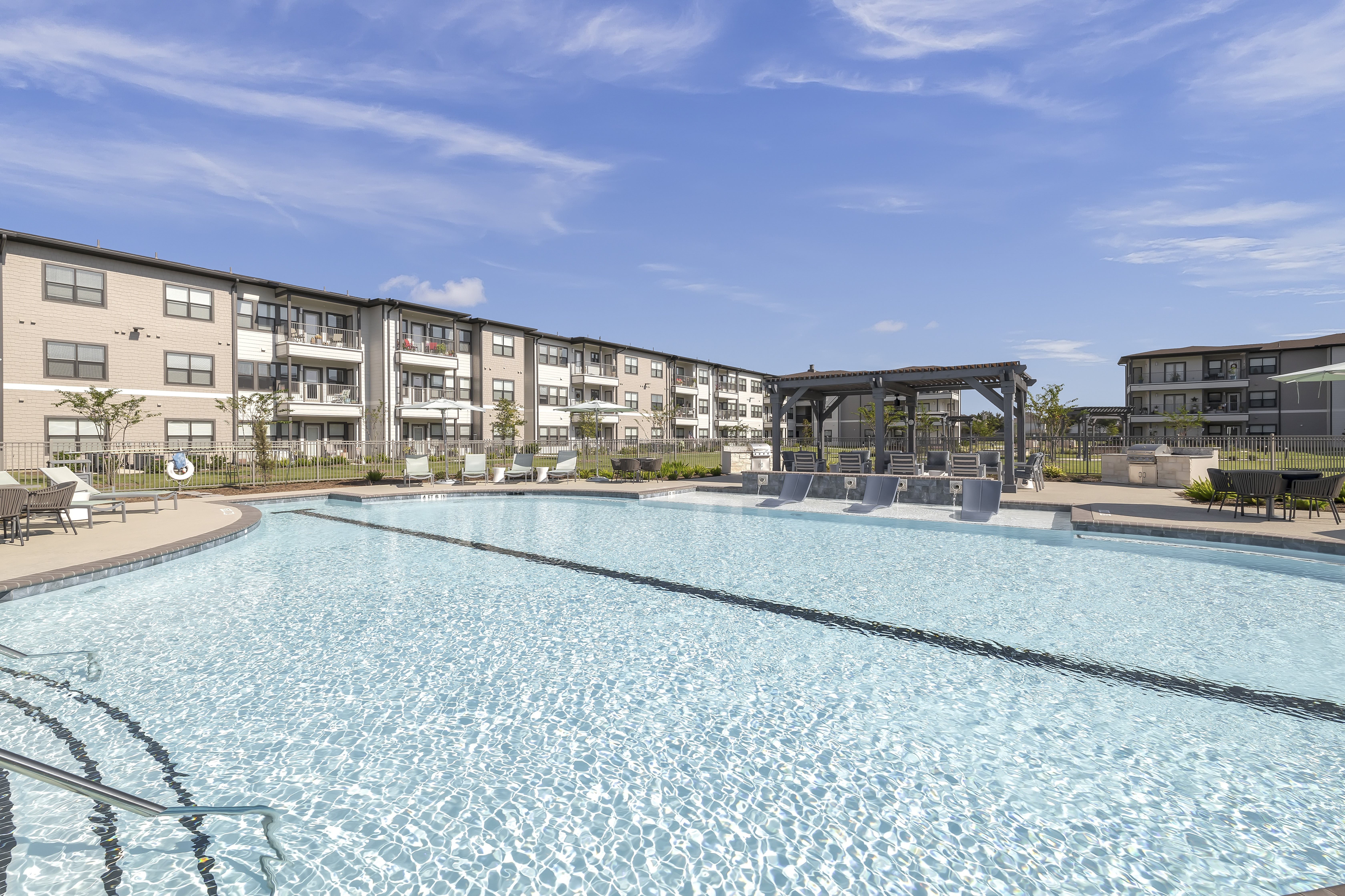 A large swimming pool in front of apartment buildings.
