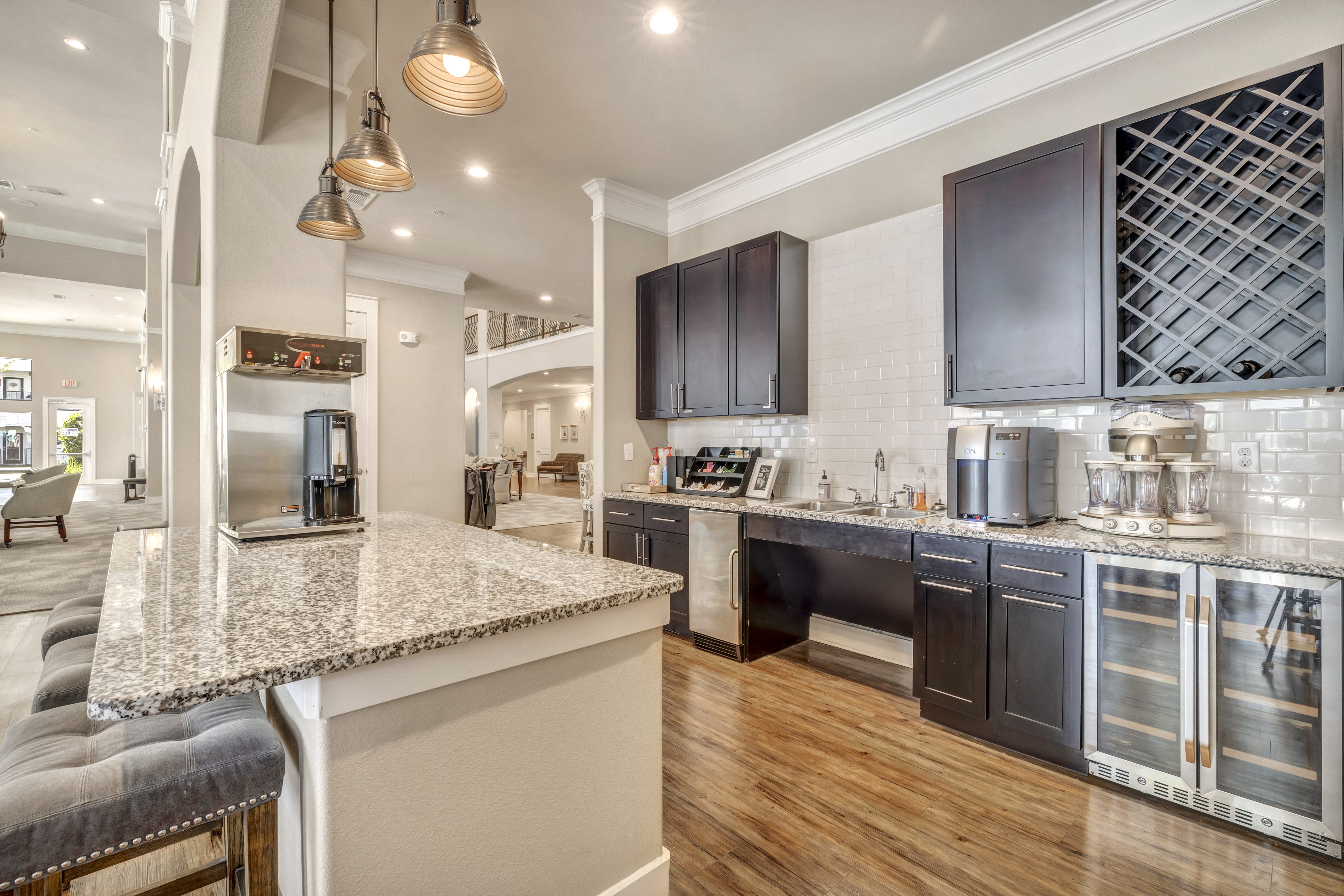 a communal clubhouse kitchen with a large island and chairs at a senior apartment community