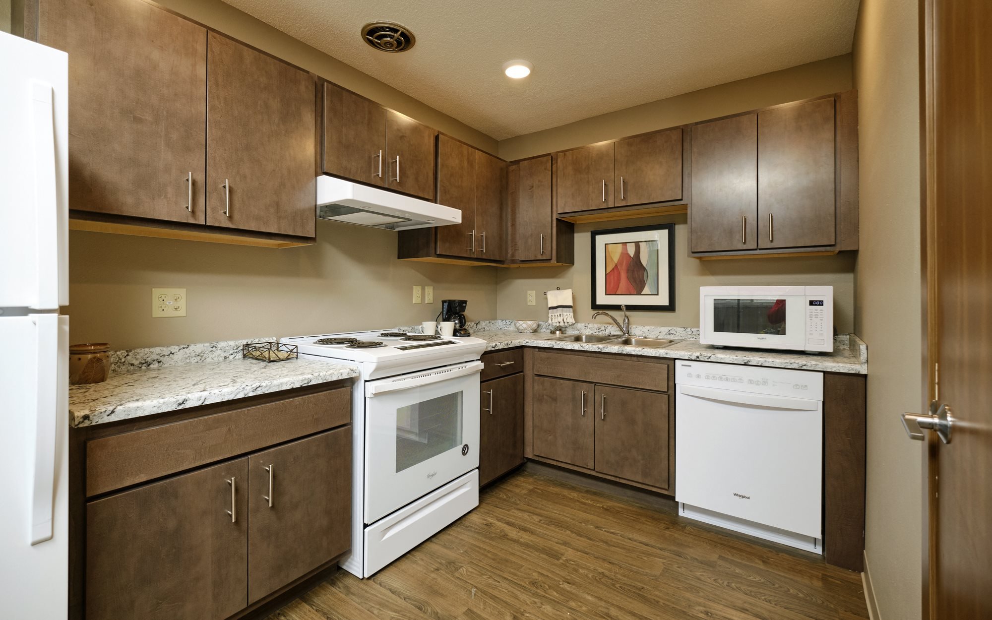 A kitchen in Sunset Apartments shows all appliances including microwave and dishwasher are included.