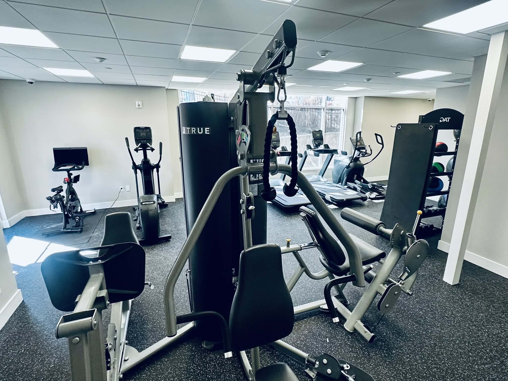 A gym with a variety of equipment including a weight machine and a stationary bike.