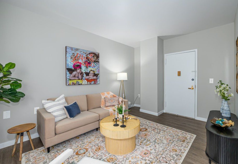 A living room with a couch, a table with a vase, and a painting on the wall.