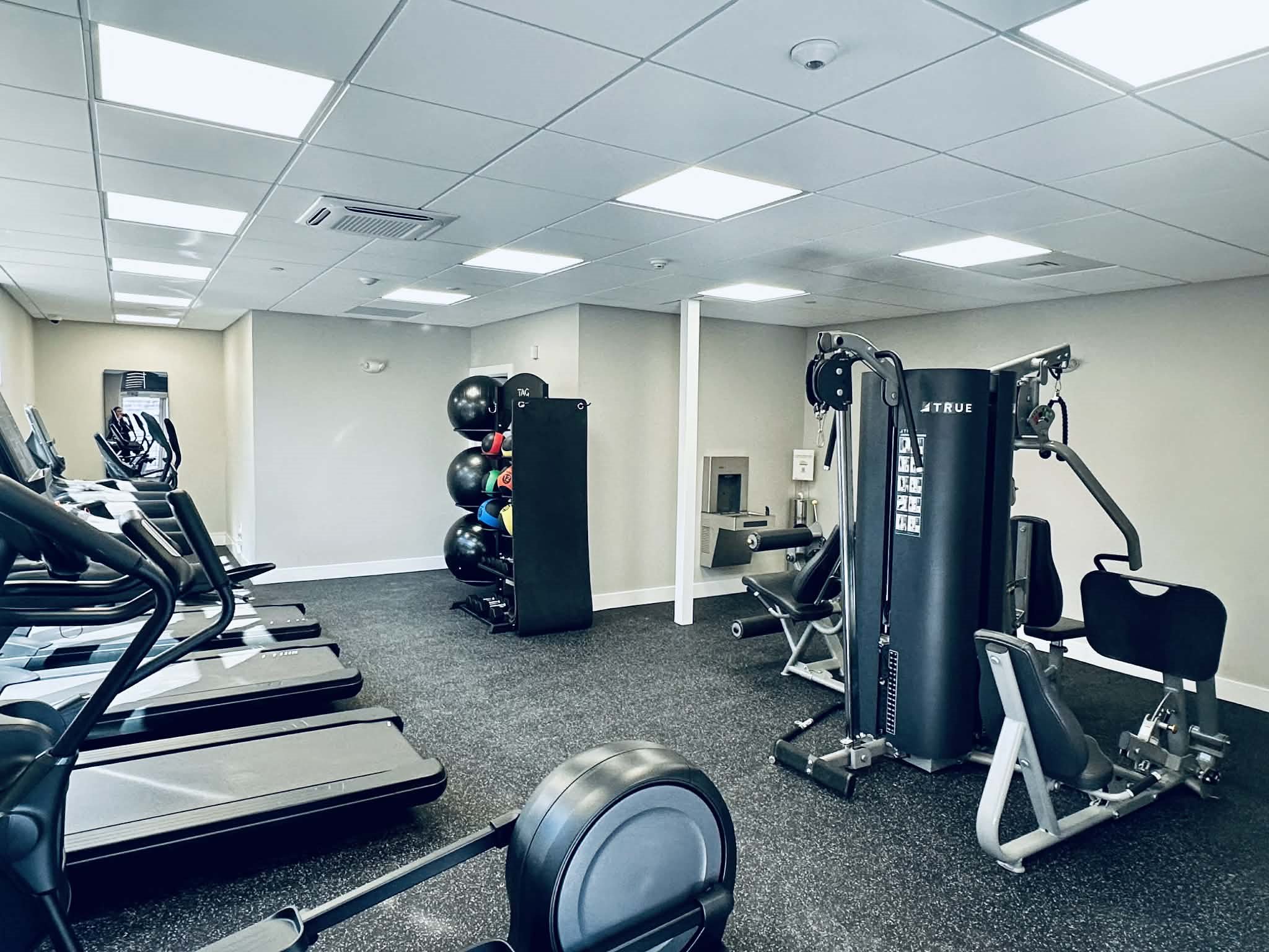 A gym with treadmills, weights, and exercise equipment.