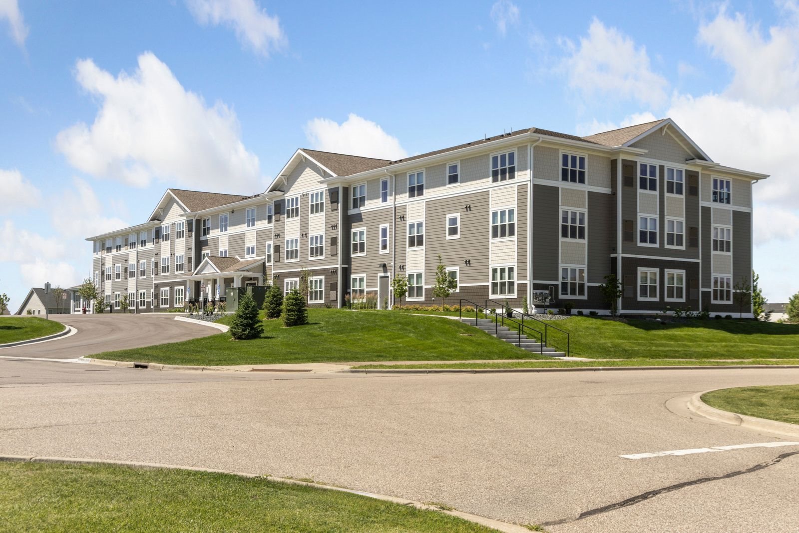 A large, multi-story apartment building with a parking lot in front.