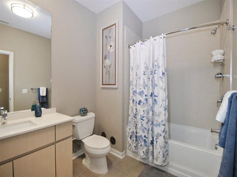 a bathroom with a white toilet next to a bath tub at The George, Ann Arbor, 48104