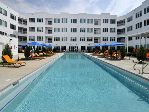 a large swimming pool with a white building in the background at The George, Ann Arbor