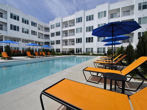 a pool with a bunch of lounge chairs and umbrellas at The George, Ann Arbor, 48104