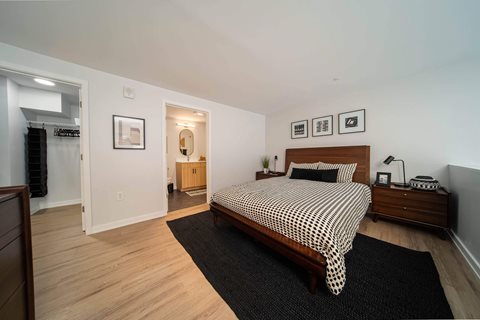 A bedroom with a bed, nightstand, and a mirror at The George, Ann Arbor, MI