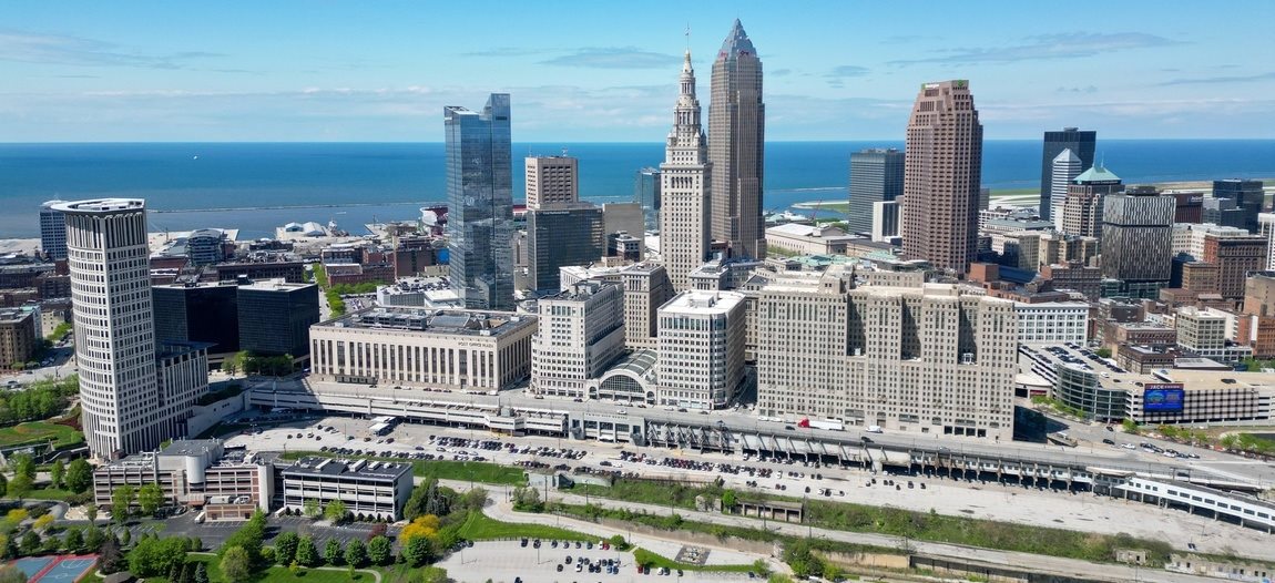 A cityscape with a large building in the center and a body of water in the background.