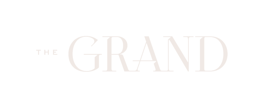 The image shows a logo with the words "THE GRAND" in white text on a black background.