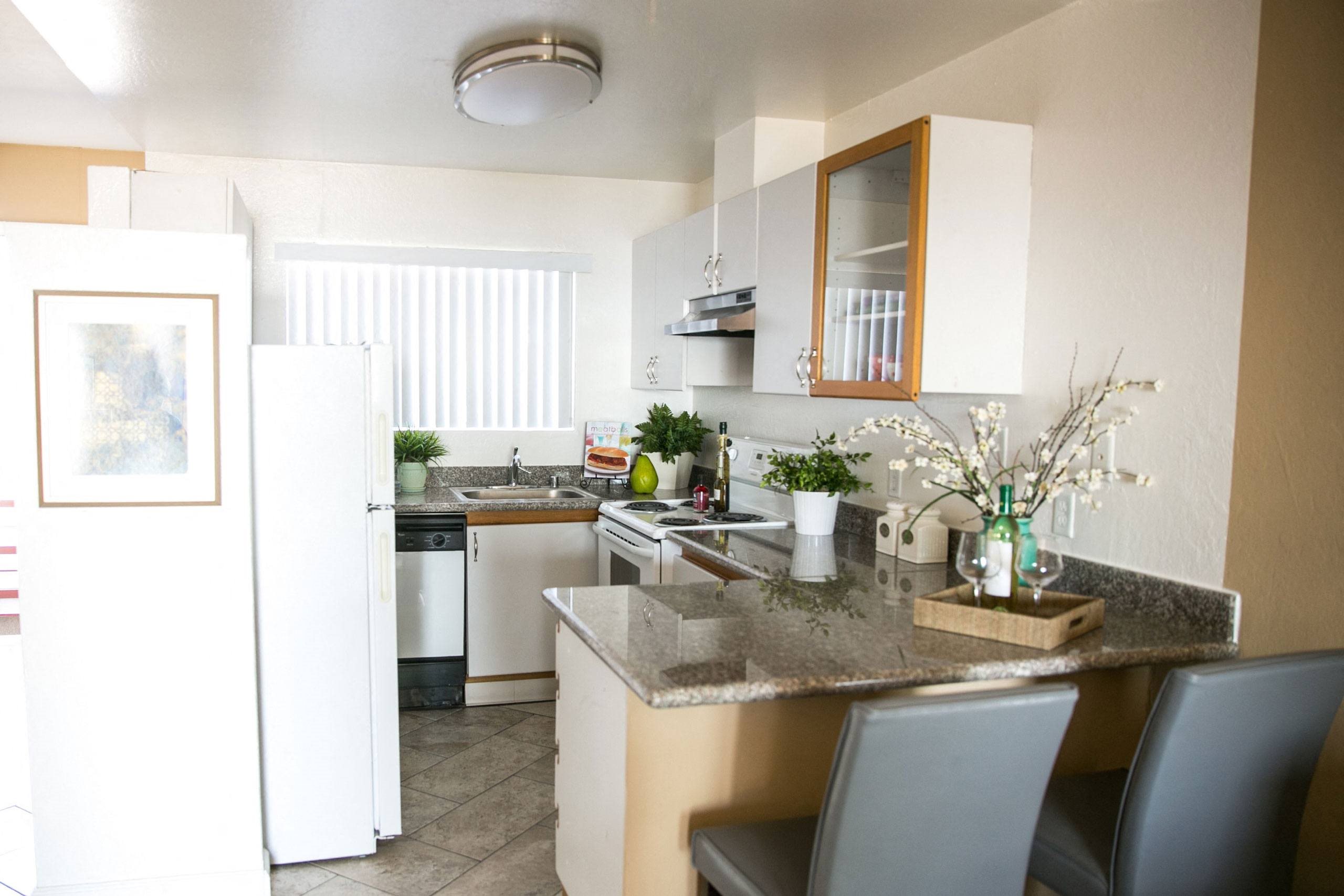 A kitchen with a white fridge and a marble counter top.