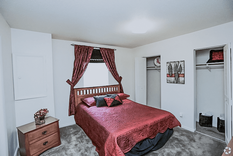 a bedroom with a bed and a dresser and a window at Gatehouse Apartments, Missouri