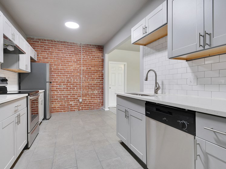 Image of kitchen with stainless steel appliances, new cabinets, and exposed brick