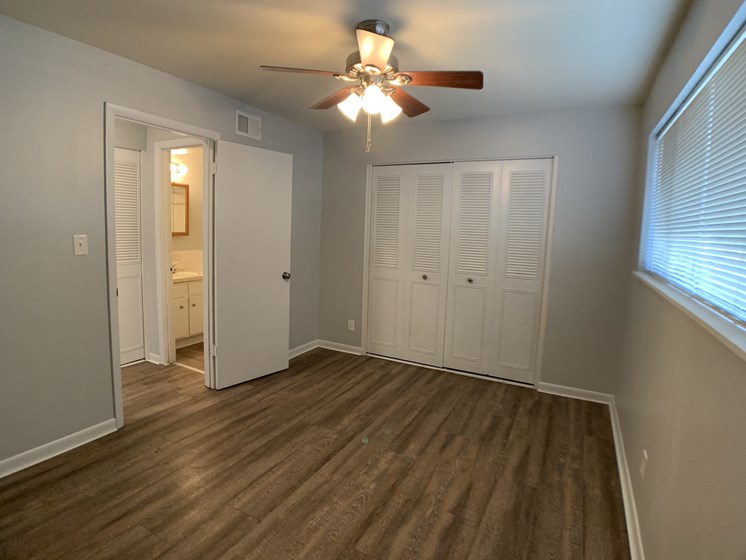 Image of a bedroom with vinyl plank flooring, large closet, and ceiling fan
