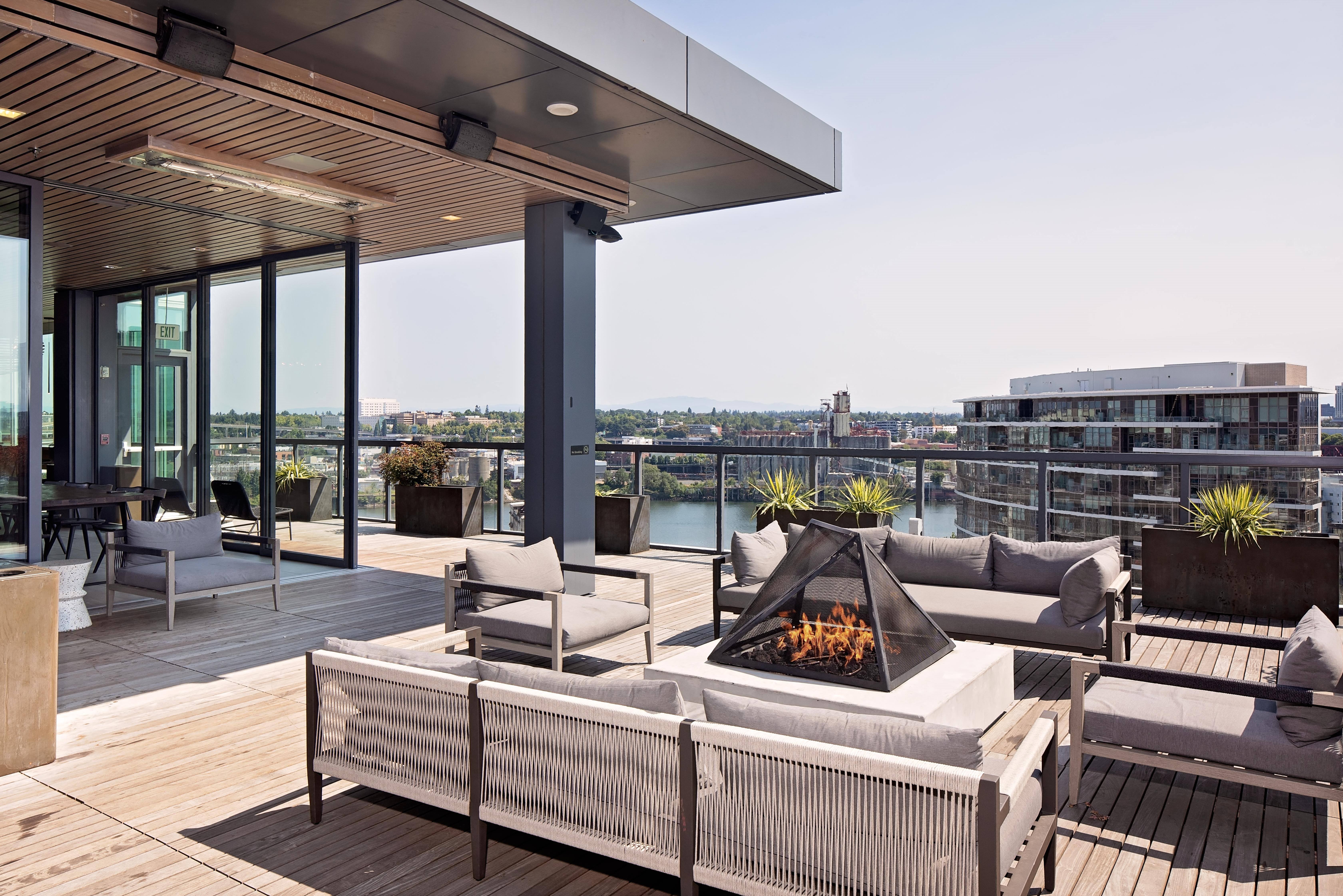 a terrace with couches and a fire pit on a roof top