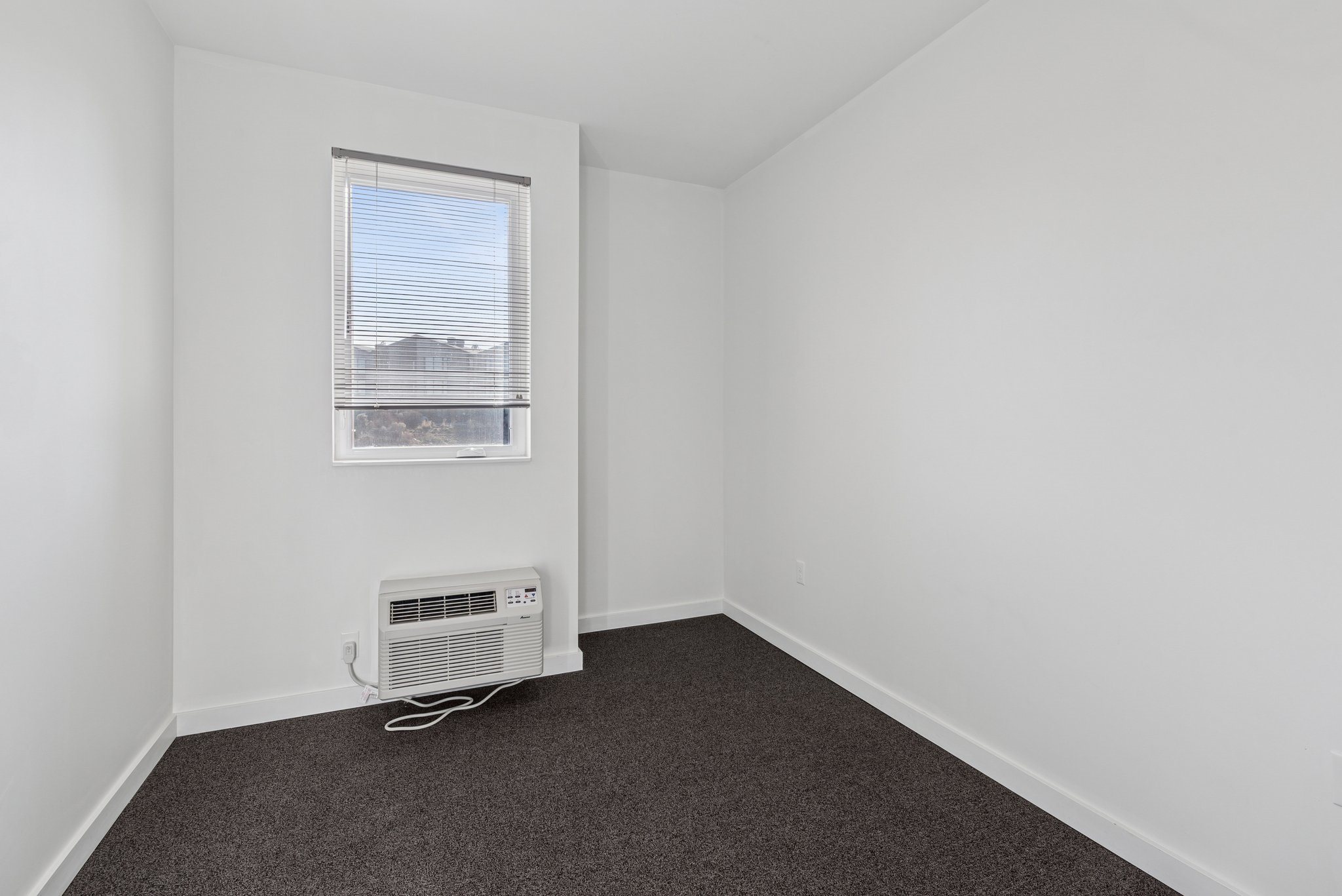 A room with a window and a fan on the floor.