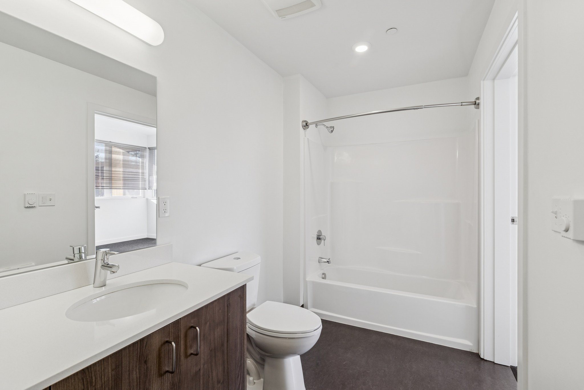 A white bathroom with a toilet, sink, and shower.