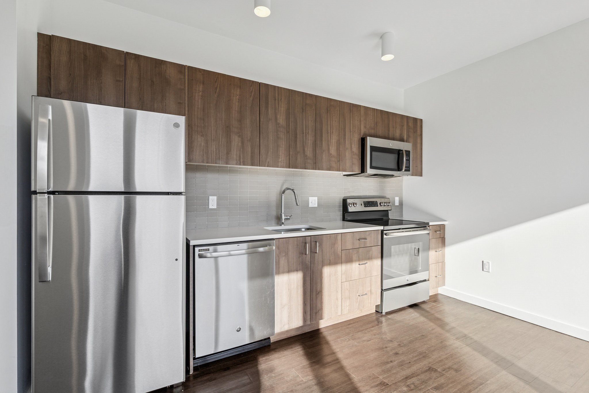 A modern kitchen with a stainless steel refrigerator and wooden cabinets.