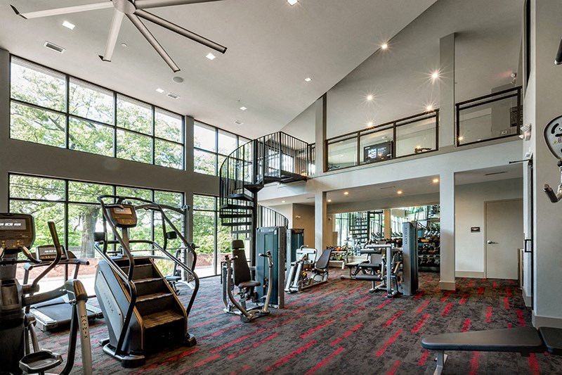 Bi-level fitness center with multiple workout equipments and large windows.