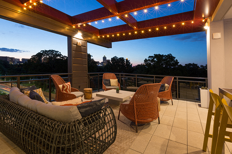 Rooftop terrace with fairy lights and seating areas during nighttime.