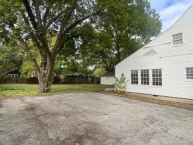 a white house with a gravel driveway and trees