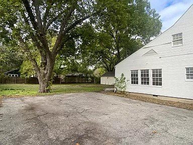 a white house with a gravel driveway and trees