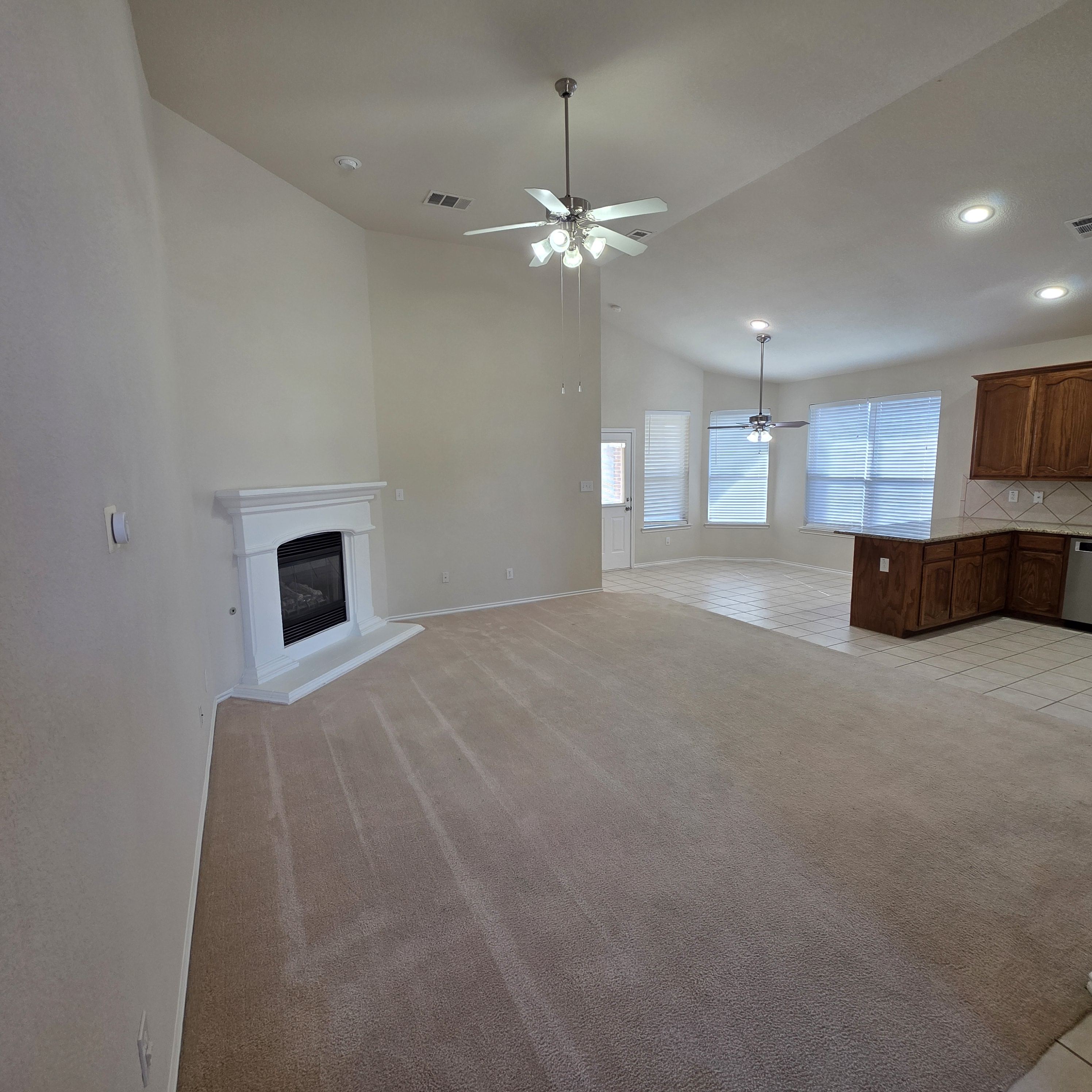 A living room with a fireplace and a ceiling fan.