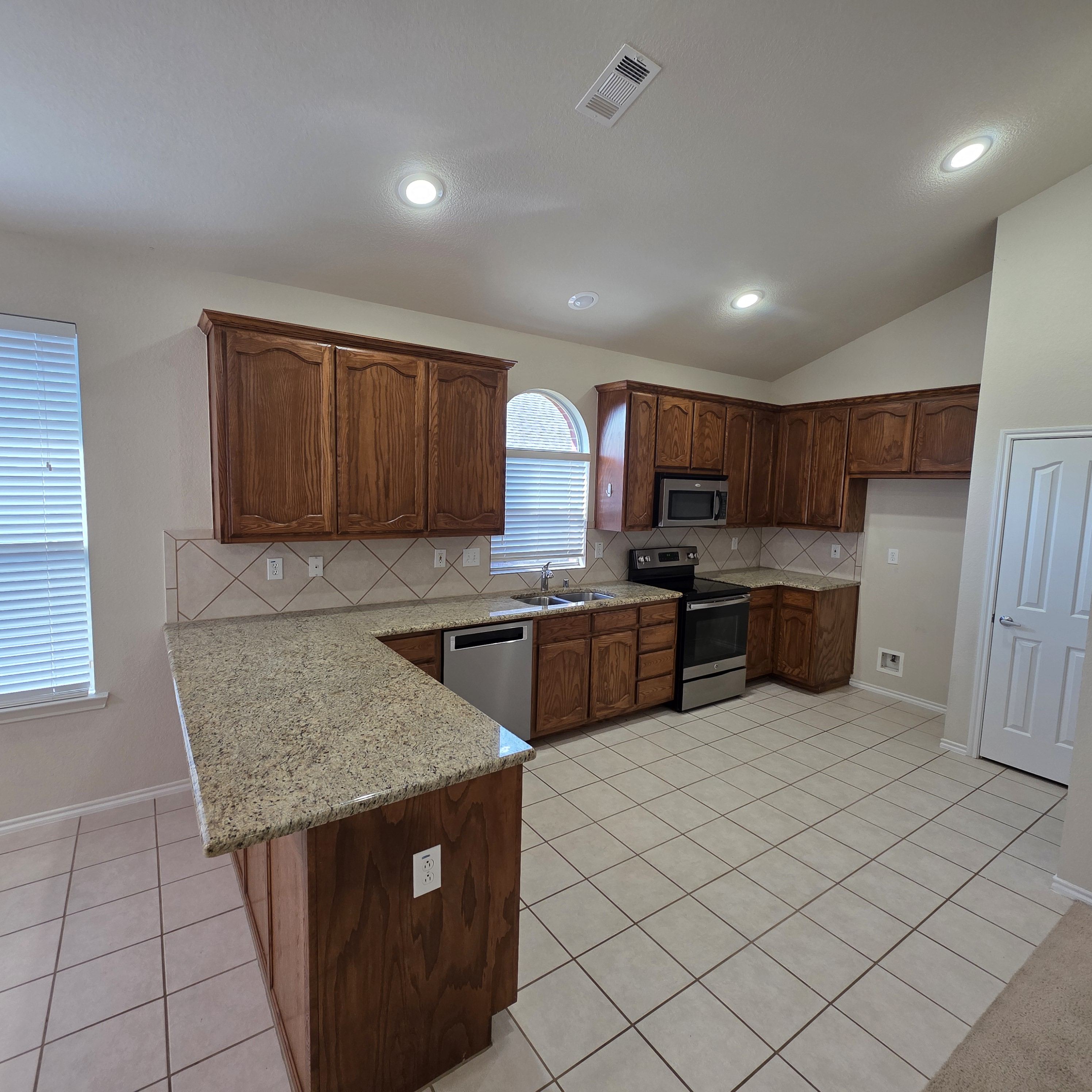 A kitchen with granite countertops and wooden cabinets.