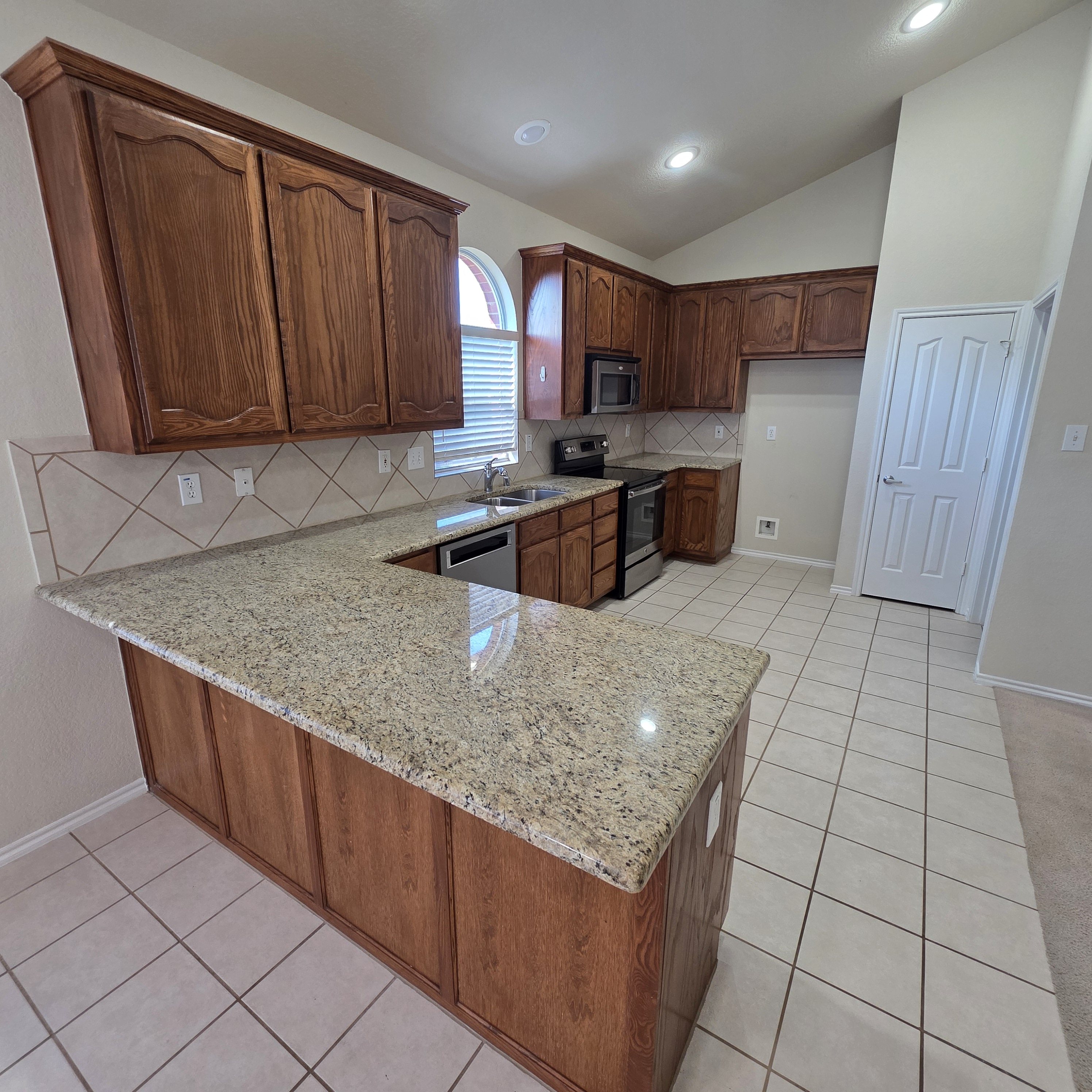 A kitchen with granite countertops and wooden cabinets.