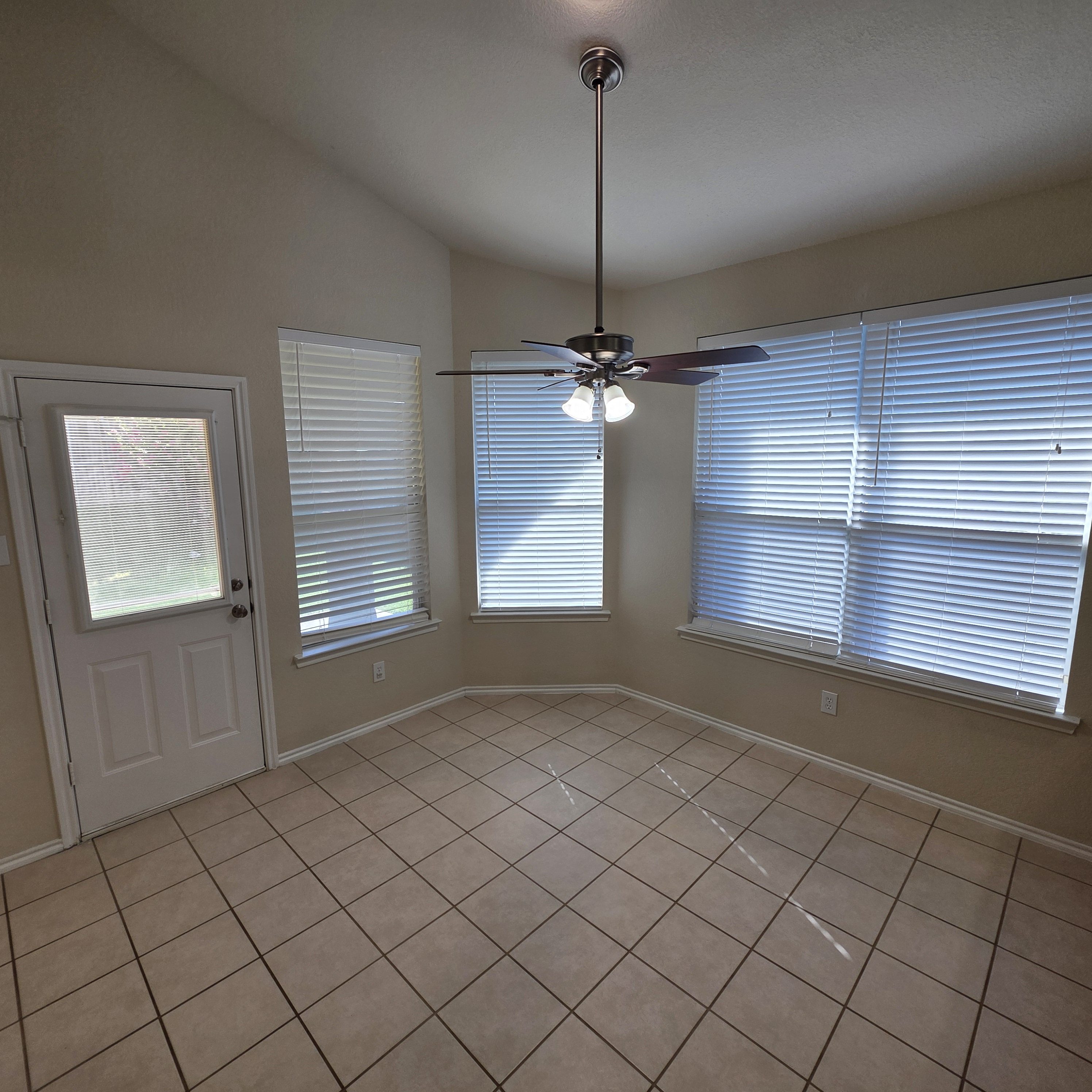 A room with a ceiling fan and tiled floor.