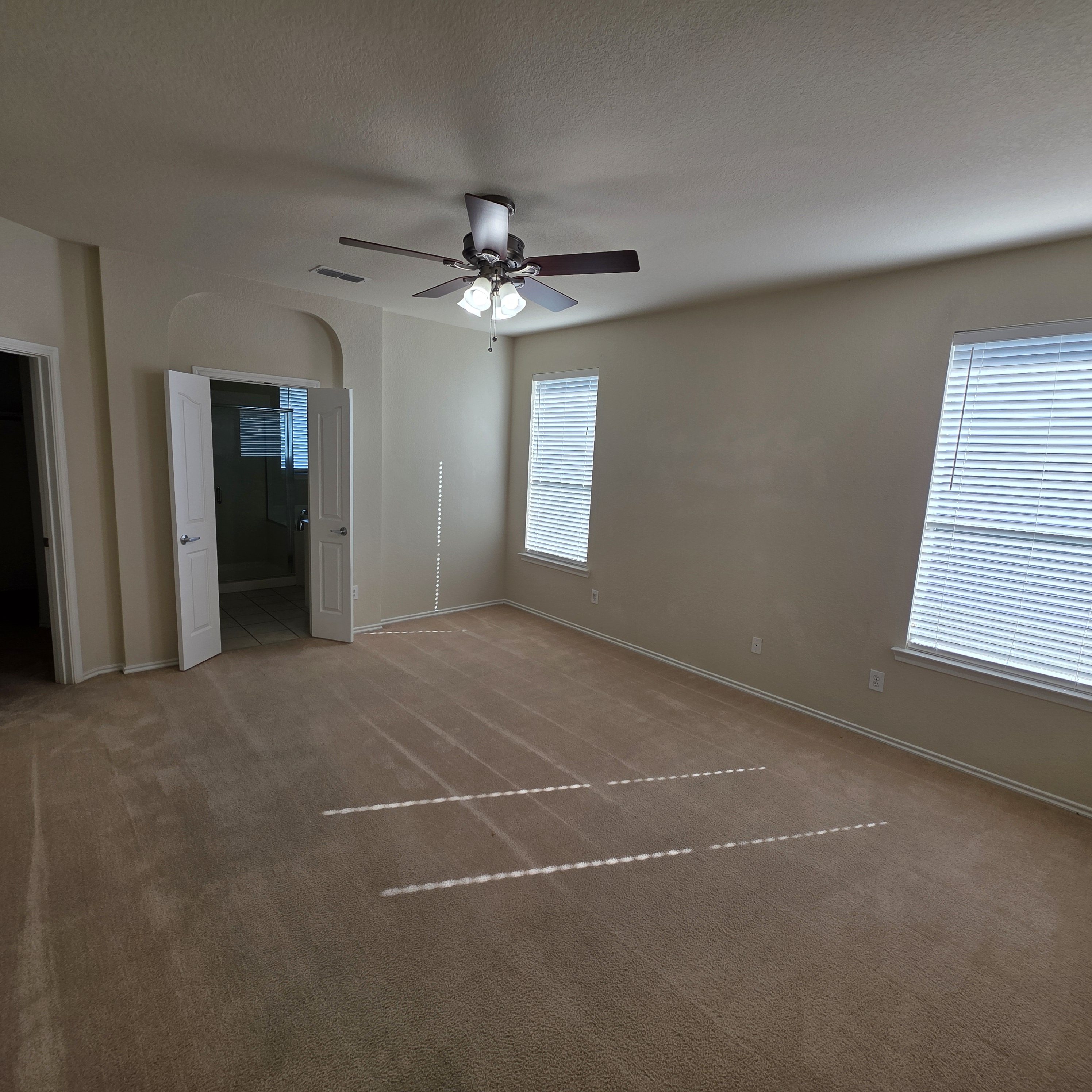 A room with a ceiling fan and carpeted floor.