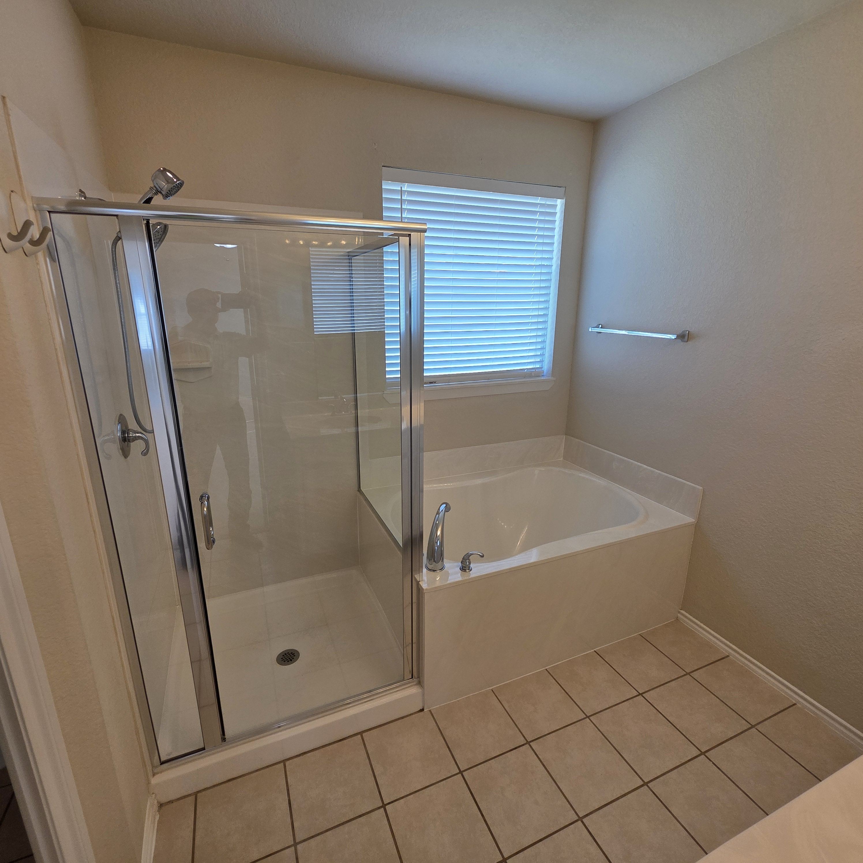 A bathroom with a glass shower door and a white bathtub.