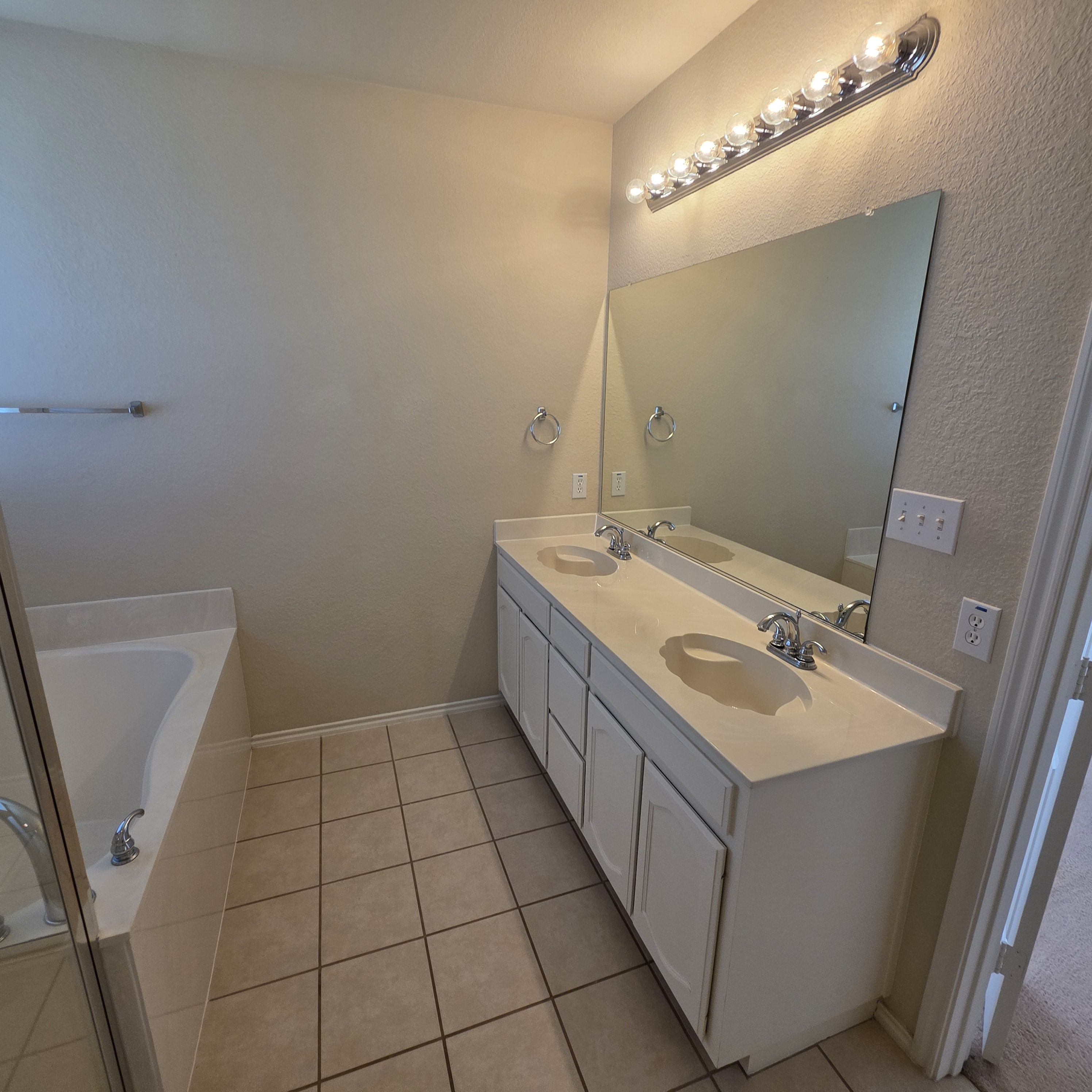 A bathroom with a white sink and a mirror with lights above it.