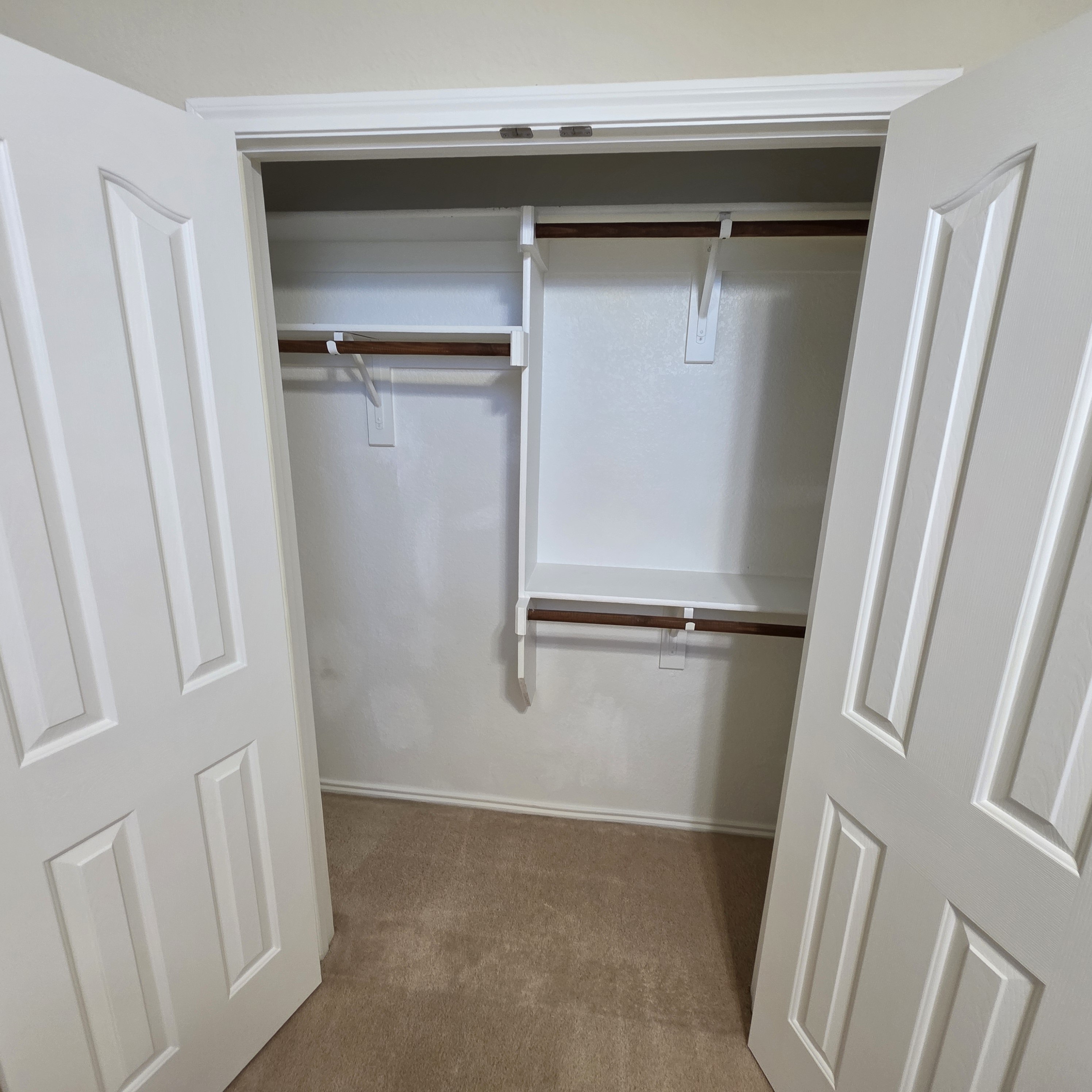 A white closet with a brown rod and a white door.