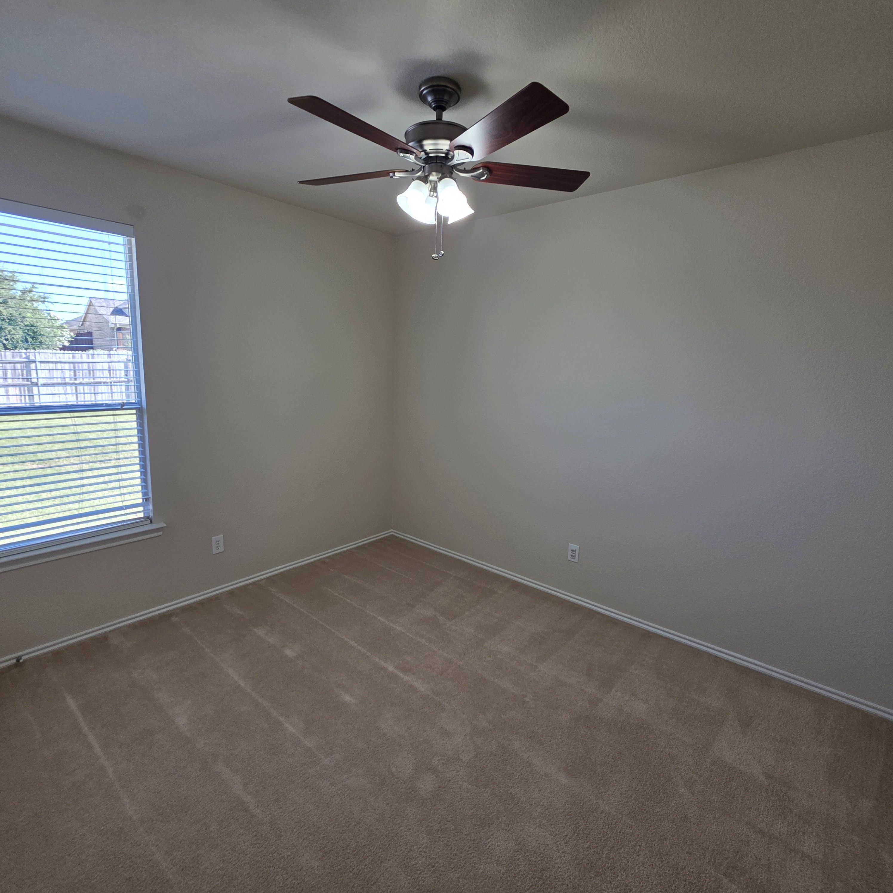 A room with a ceiling fan and carpeted floor.