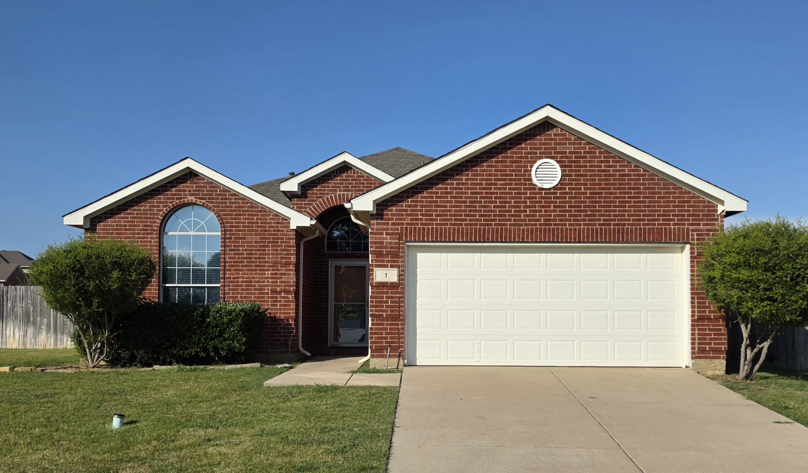 A red brick house with a white garage door.