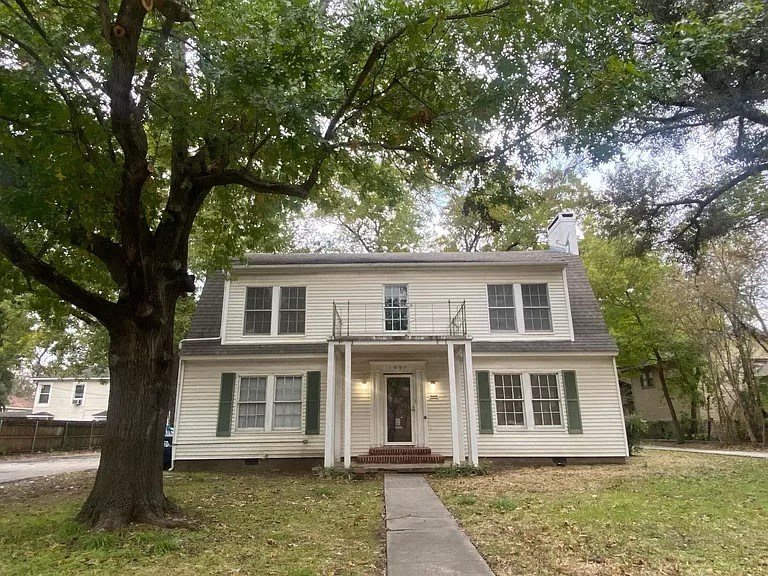 a white house with a tree and a sidewalk