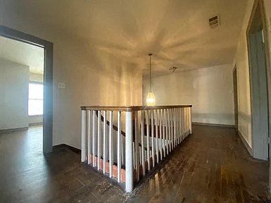 an empty living room with a railing and a light