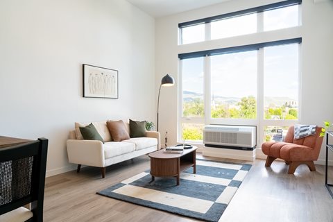 A living room with a couch, a table, and a large window.
