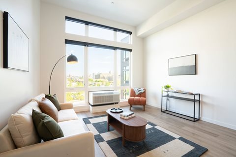 A living room with a white couch, a coffee table, and a large window.