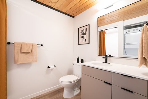 A white toilet sits in a bathroom with a wooden ceiling.