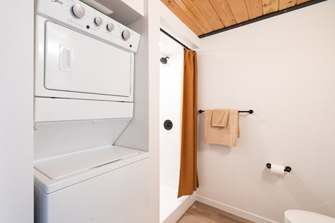 A white oven and a bathroom with a towel hanging on the hook.