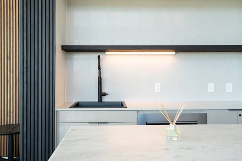 A modern kitchen with a marble countertop and a black faucet.