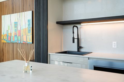 A modern kitchen with a marble countertop and a painting on the wall.