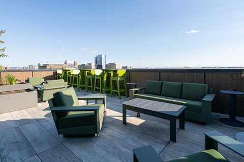 A patio with green furniture and a view of the city.