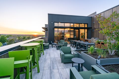 A modern outdoor seating area with green chairs and tables.
