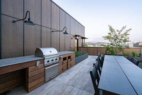 A modern outdoor kitchen with a grill and bar stools.